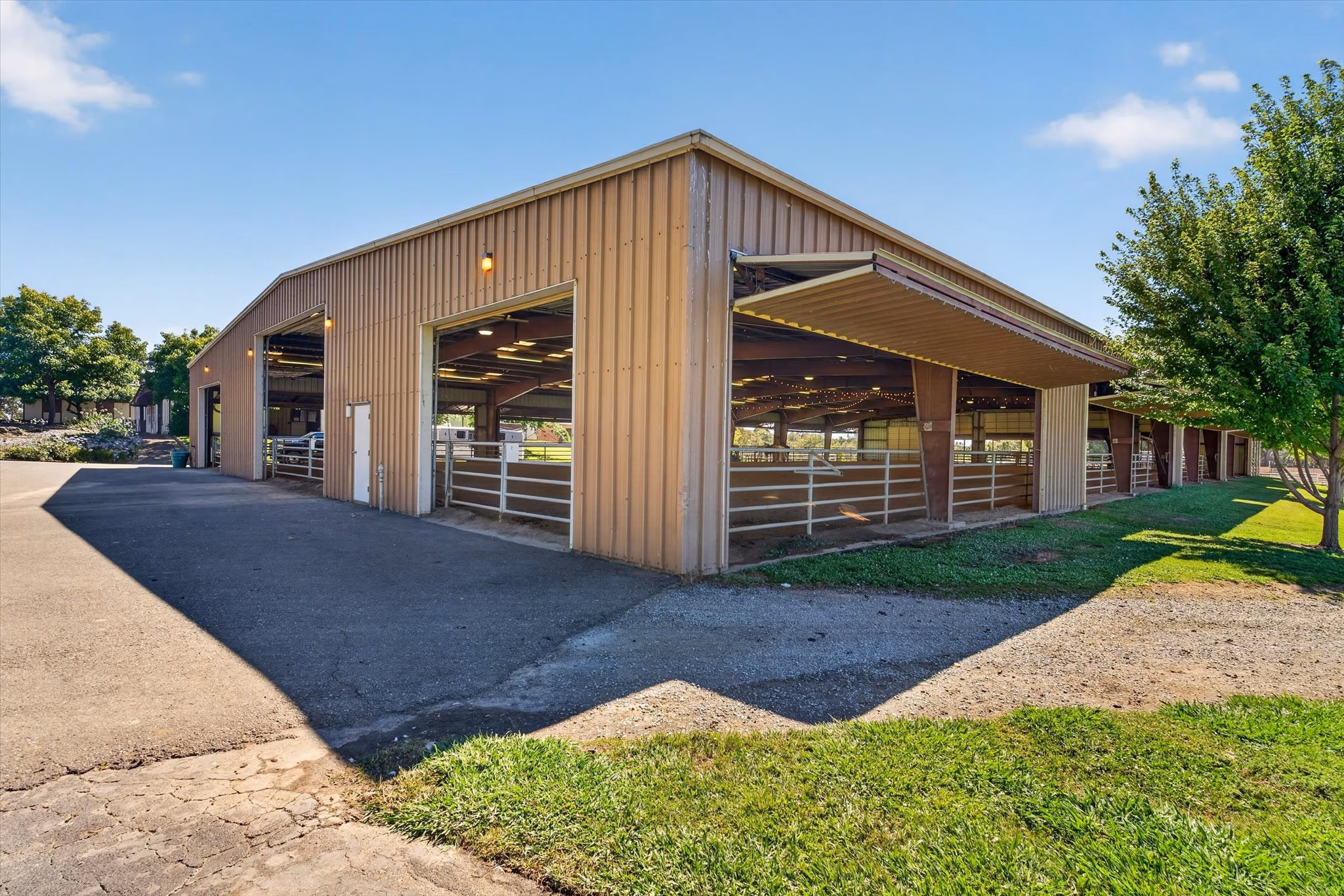 The covered arena from outside, a long clear-span building with its side doors raised.